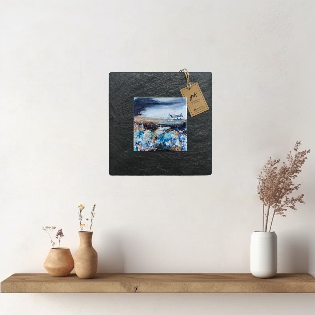 A ceramic tile print of a colourful painting titled 'Bluebells', showing a small house nestled in the Scottish Highlands, available mounted on natural slate or framed.