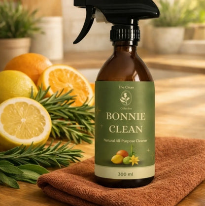Bottle of Bonnie Clean natural all-purpose cleaner with lemons and oranges and a cleaning cloth on a wooden surface