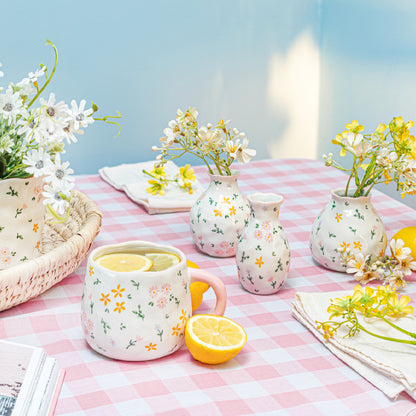 Mug with floral design on a checkered tablecloth with lemons and flowers.