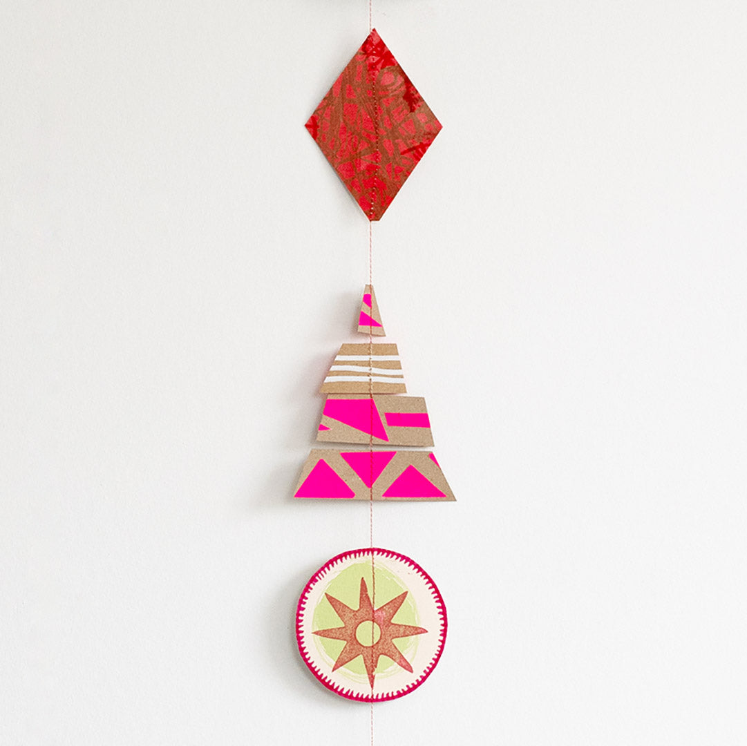 Vertical hanging Christmas garland made of 12 colourful, modern shapes cut from recycled and hand-painted card prints.