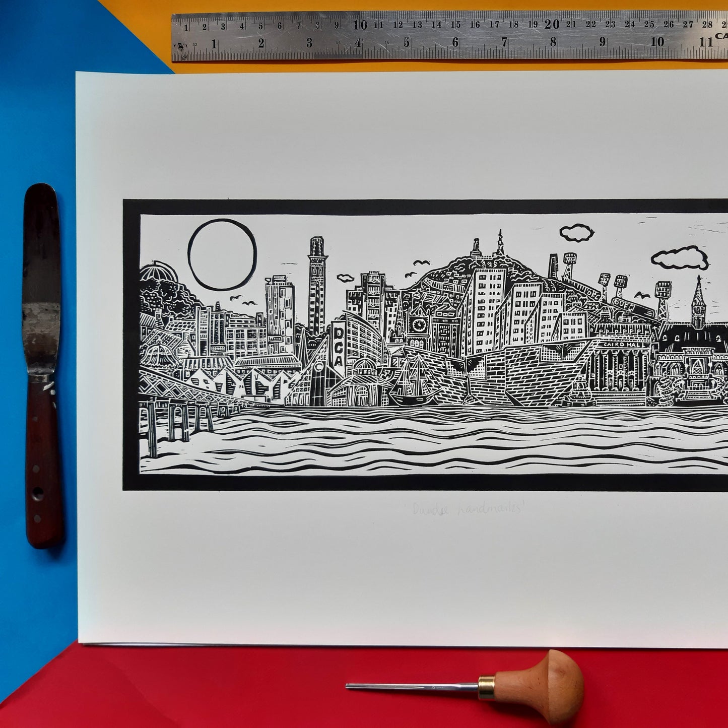 Dundee Cityscape Black and White Lino Print on a colourful background with a ruler at the top