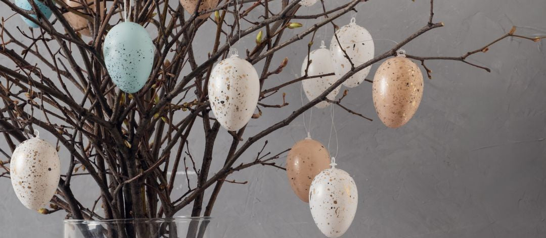 Decorative Easter eggs hanging from branches in glass vase