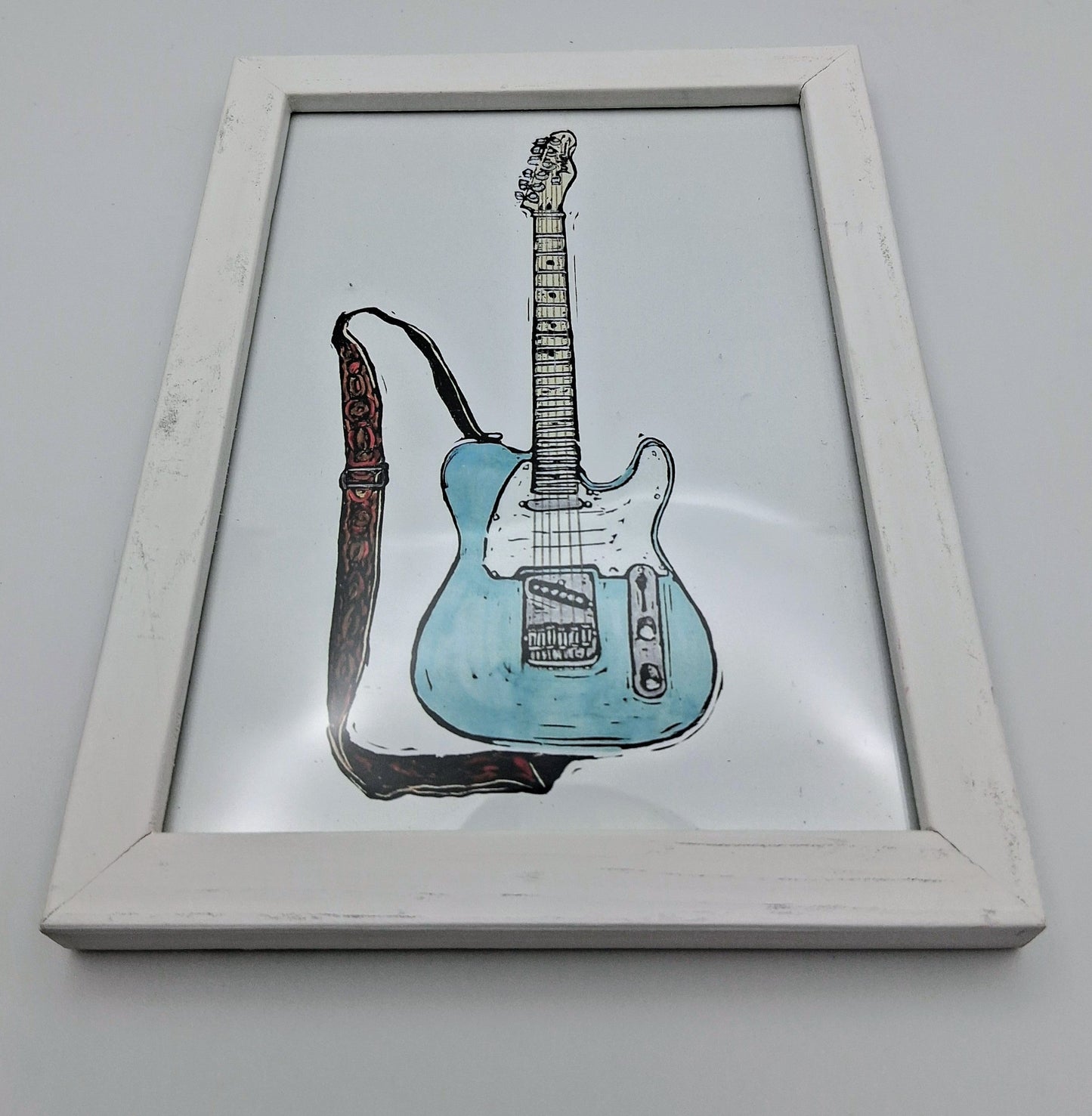 Bee Birds lino print picture of a pale blue and white electric guitar in a small white frame