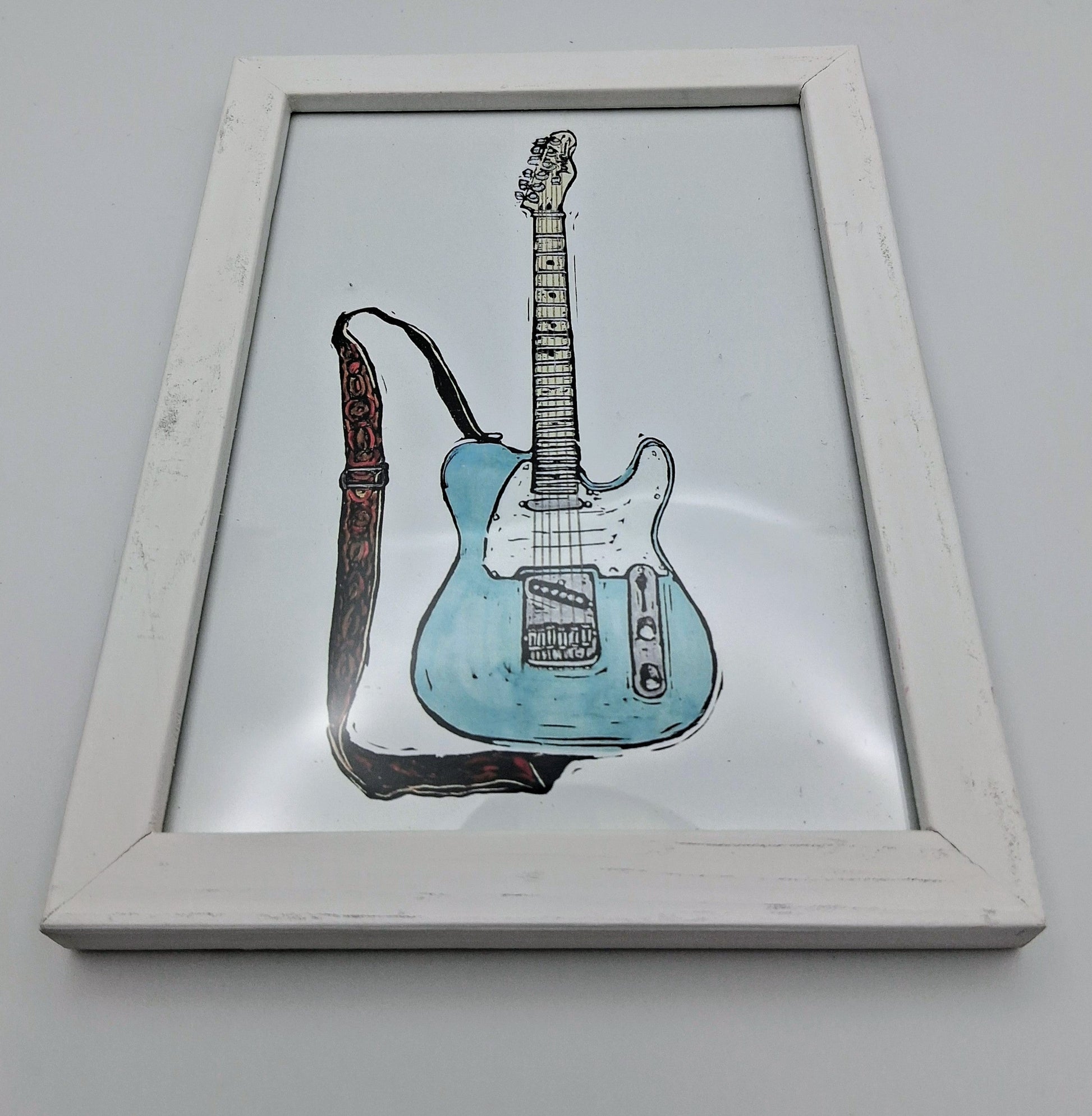 Bee Birds lino print picture of a pale blue and white electric guitar in a small white frame