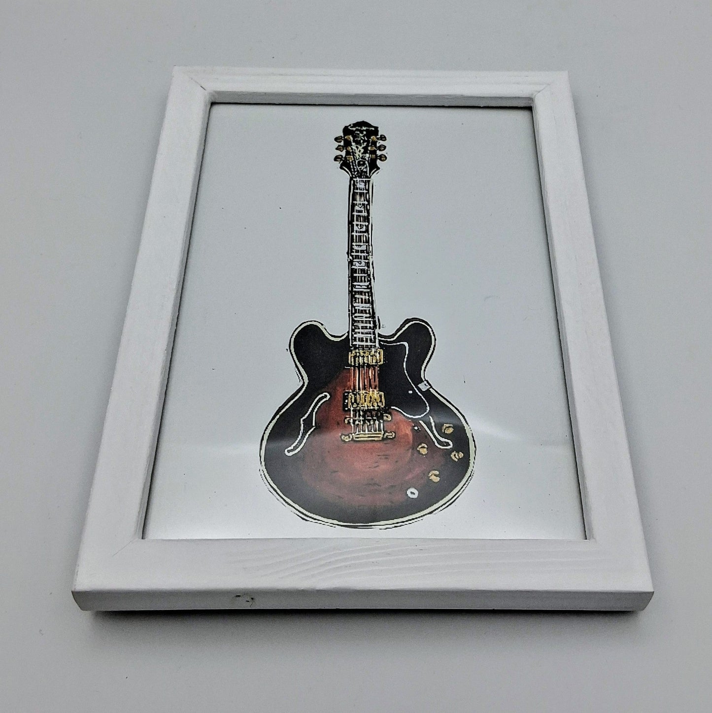 Bee Birds lino print picture of a brown acoustic guitar in a small white frame