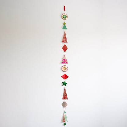 Vertical hanging Christmas garland made of 12 colourful, modern shapes cut from recycled and hand-painted card prints.