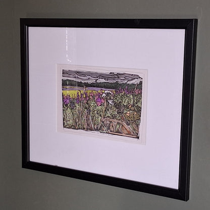 A colourful linocut print by BeeBirds depicting a scenic view of Glen Clova in Angus, highlighting lavender and fireweed, mounted in a black frame.