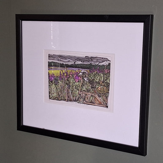 A colourful linocut print by BeeBirds depicting a scenic view of Glen Clova in Angus, highlighting lavender and fireweed, mounted in a black frame.