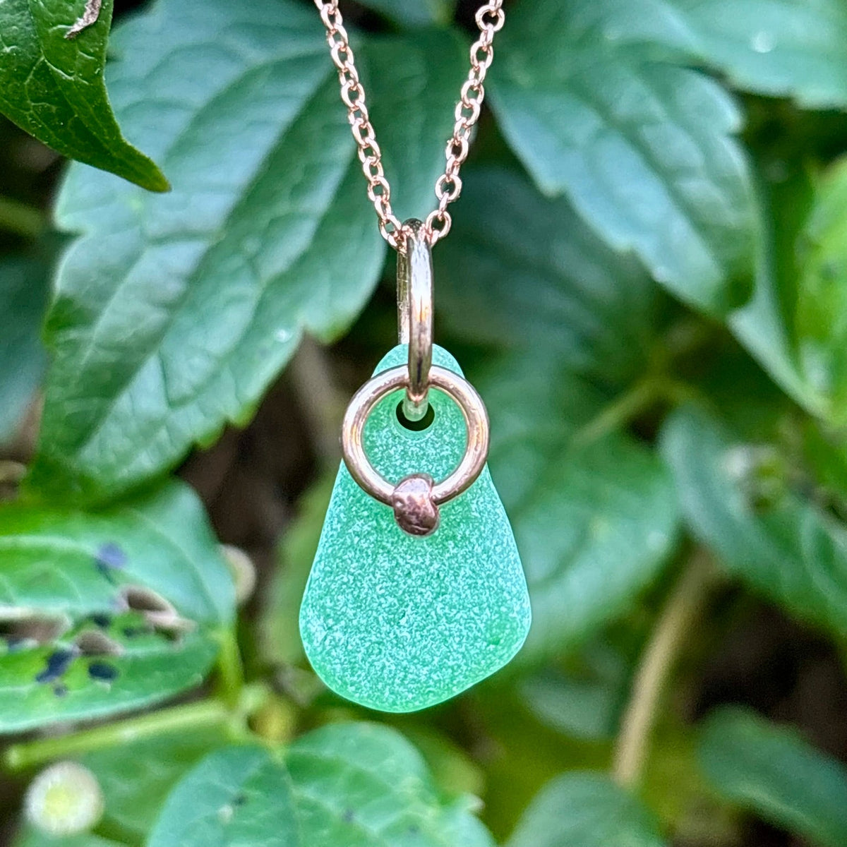 Rowan Berry Jewellery sea glass and hag stone necklace featuring frosted seafoam sea glass, a handcrafted copper hag stone and two bronze hoops on a rose gold-plated chain.