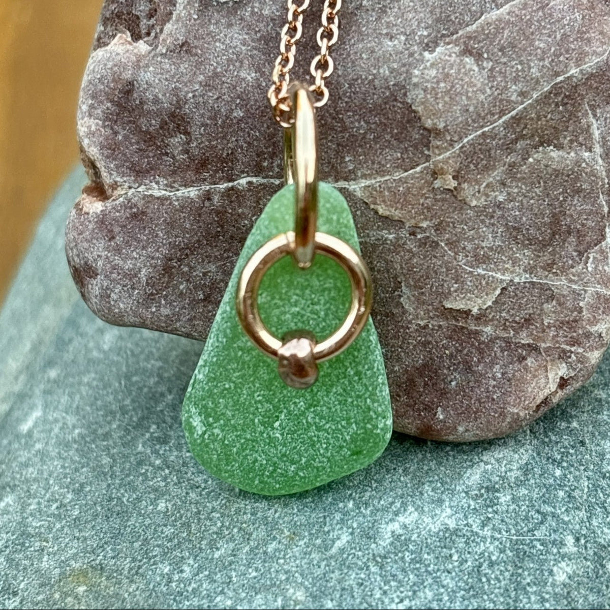 Rowan Berry Jewellery sea glass and hag stone necklace featuring frosted seafoam sea glass, a handcrafted copper hag stone and two bronze hoops on a rose gold-plated chain.