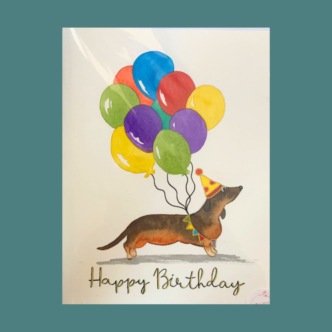 Hand-painted birthday card featuring a dachshund with colourful balloons and a party hat, with the text 'Happy Birthday' at the bottom.