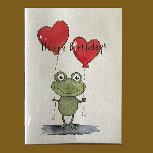 Hand-painted watercolor birthday card with a frog holding heart shaped balloons, signed by Lill Casas.