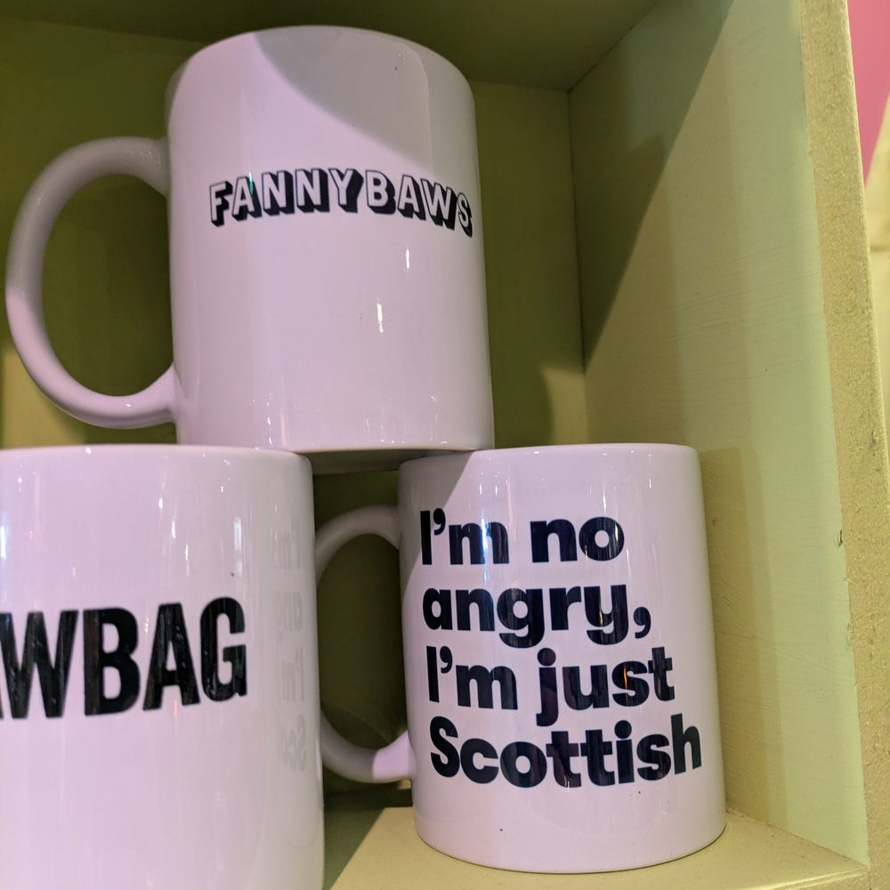 A display of white ceramic mugs with bold, funny text decals in modern, wrap-around designs.