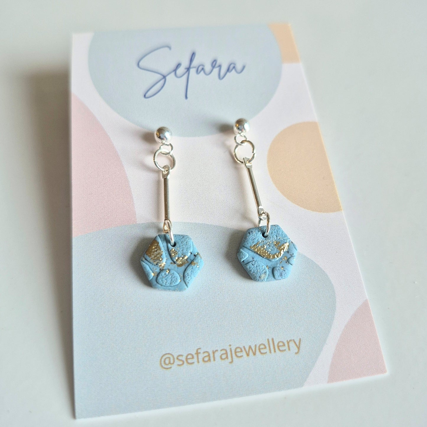 Blue sand hexagon-shaped earrings on a colourful card with 'Sefara' branding
