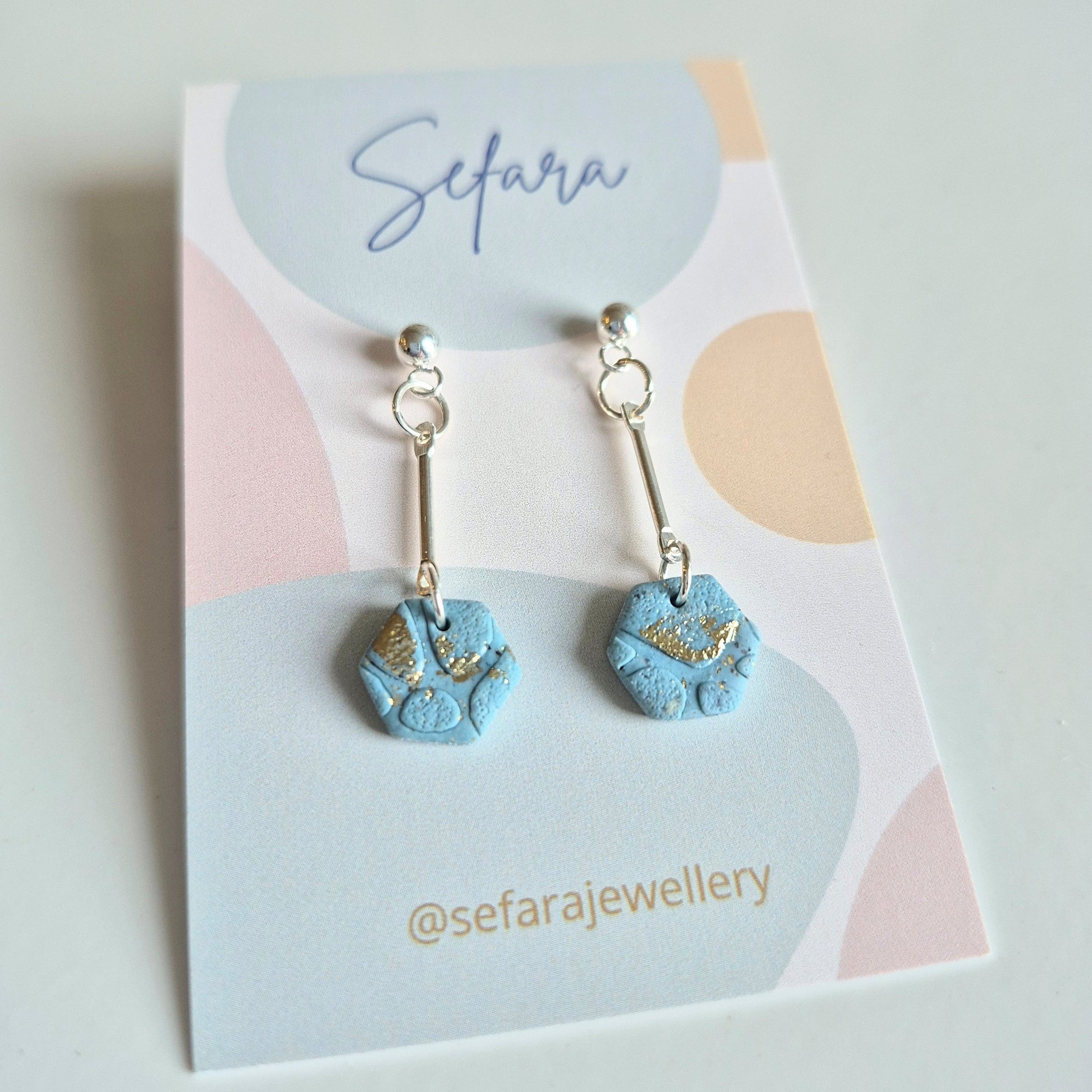 Blue sand hexagon-shaped earrings on a colourful card with 'Sefara' branding