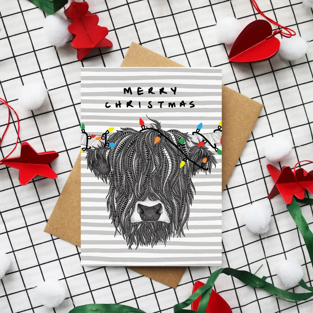 Highland Cow Christmas card featuring hand-drawn festive coo illustration by Kilo Papa Studio with Kraft envelope.