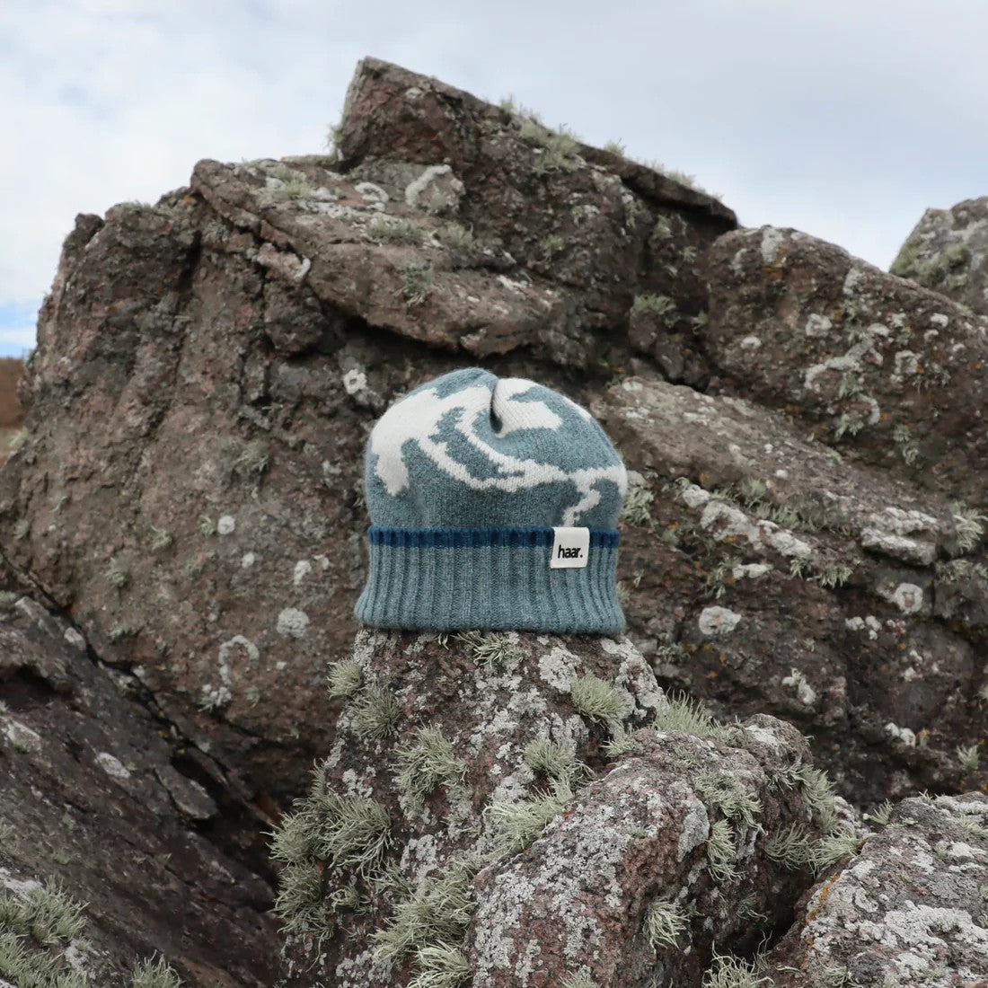 Close-up of a textured lambswool beanie hat, showing the quality of the knit and natural colourway, representing the weathered rocks and sand of the Scottish coast.
