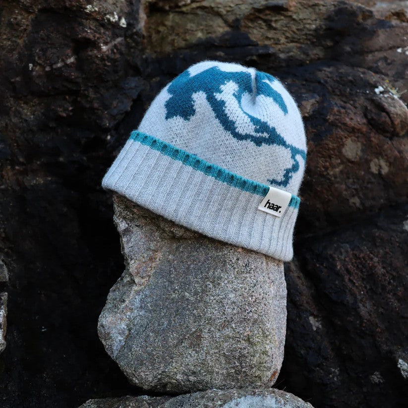 Close-up of a textured lambswool beanie hat, showing the quality of the knit and natural colourway, representing the weathered rocks and sand of the Scottish coast.