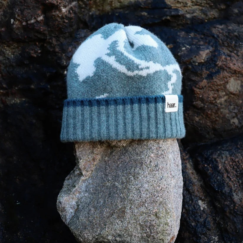 Close-up of a textured lambswool beanie hat, showing the quality of the knit and natural colourway, representing the weathered rocks and sand of the Scottish coast.