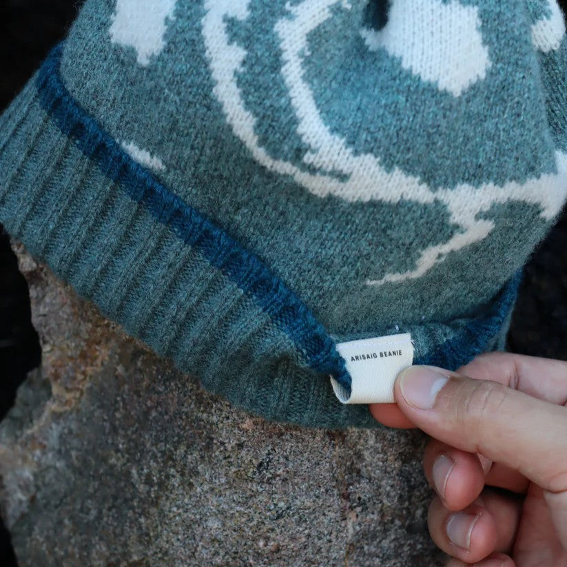 Close-up of a textured lambswool beanie hat, showing the quality of the knit and natural colourway, representing the weathered rocks and sand of the Scottish coast.