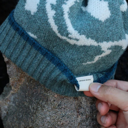 Close-up of a textured lambswool beanie hat, showing the quality of the knit and natural colourway, representing the weathered rocks and sand of the Scottish coast.