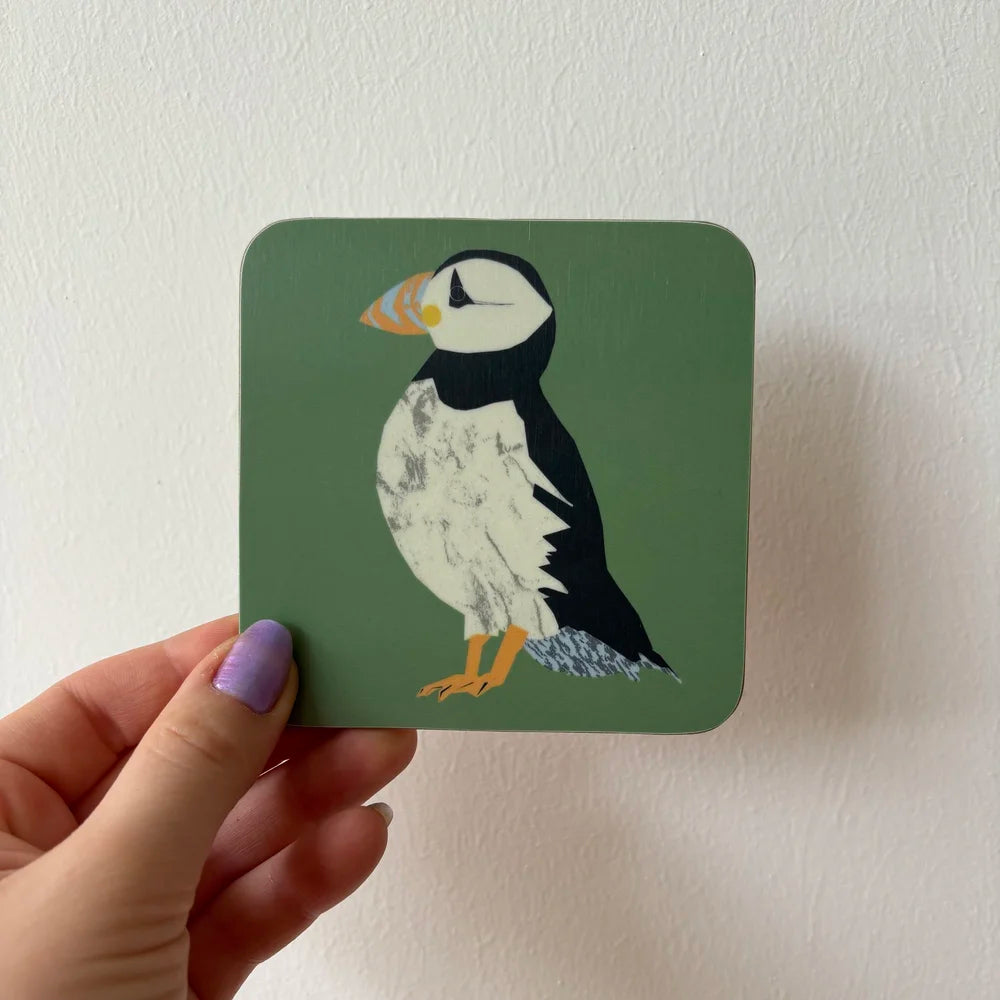 Coaster with puffin design held by a hand against a white background