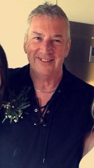 John Dowie pictured on his wedding day wearing a dark blue shirt, thistle button whole and necklace.