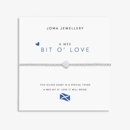 A silver Joma bracelet with a heart charm, packaged in a card that reads 'A Wee BIT O' LOVE'.