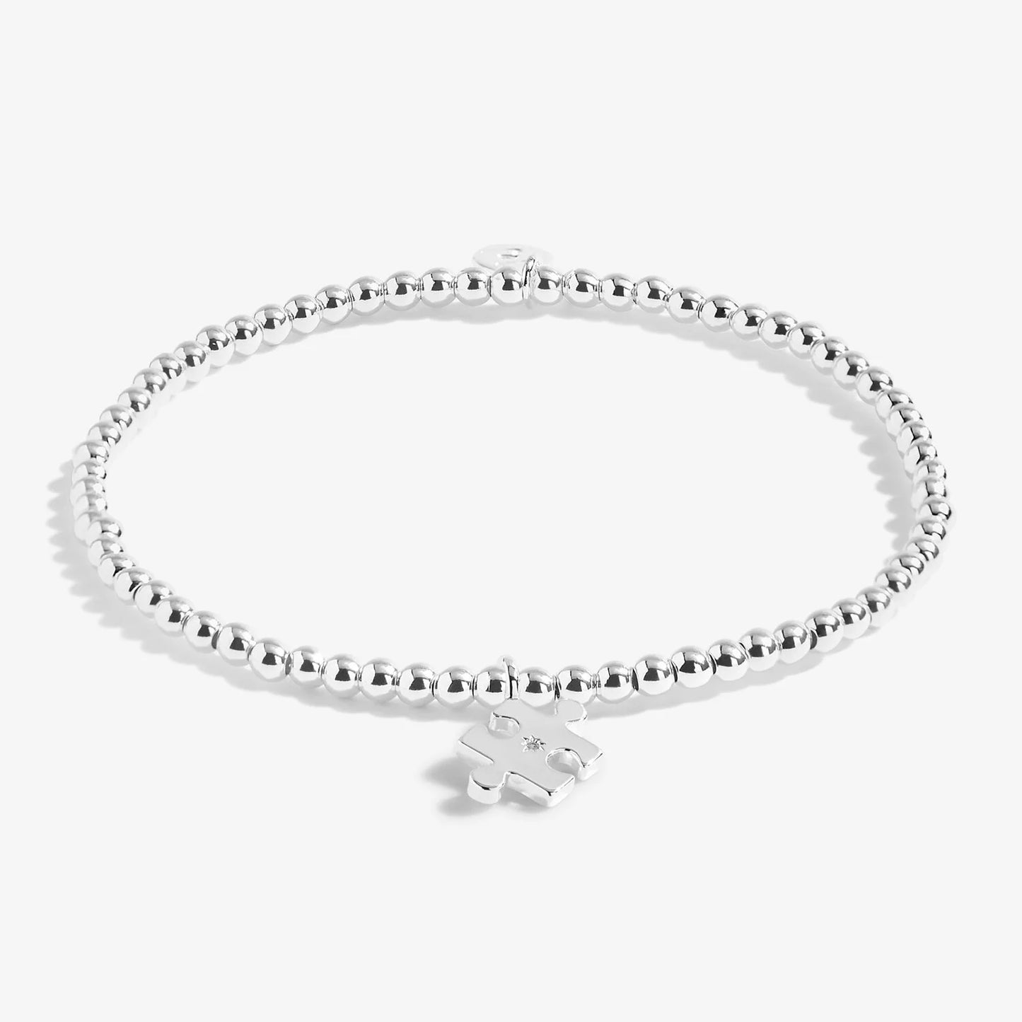 A silver plated stretch beaded bracelet with a puzzle piece charm