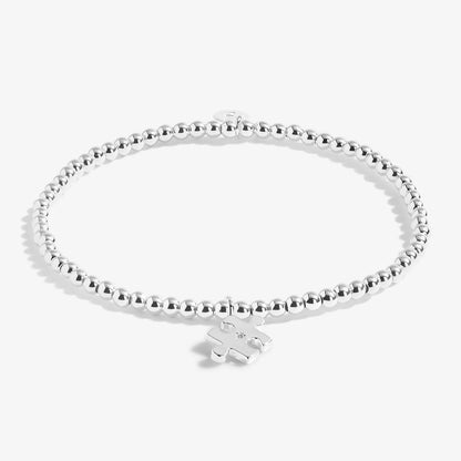 A silver plated stretch beaded bracelet with a puzzle piece charm