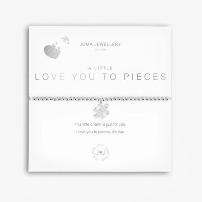 A silver bracelet with a puzzle piece charm, packaged in a card that reads 'A Little LOVE YOU TO PIECES'.