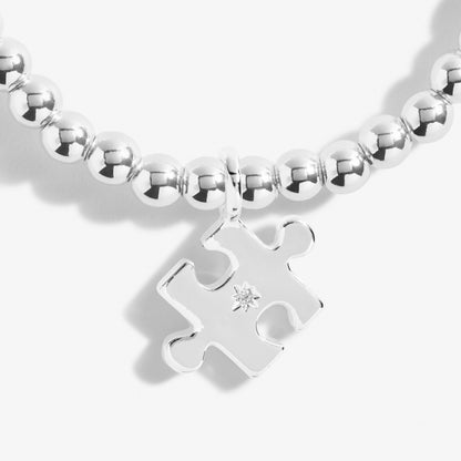 A silver plated stretch beaded bracelet with a puzzle piece charm