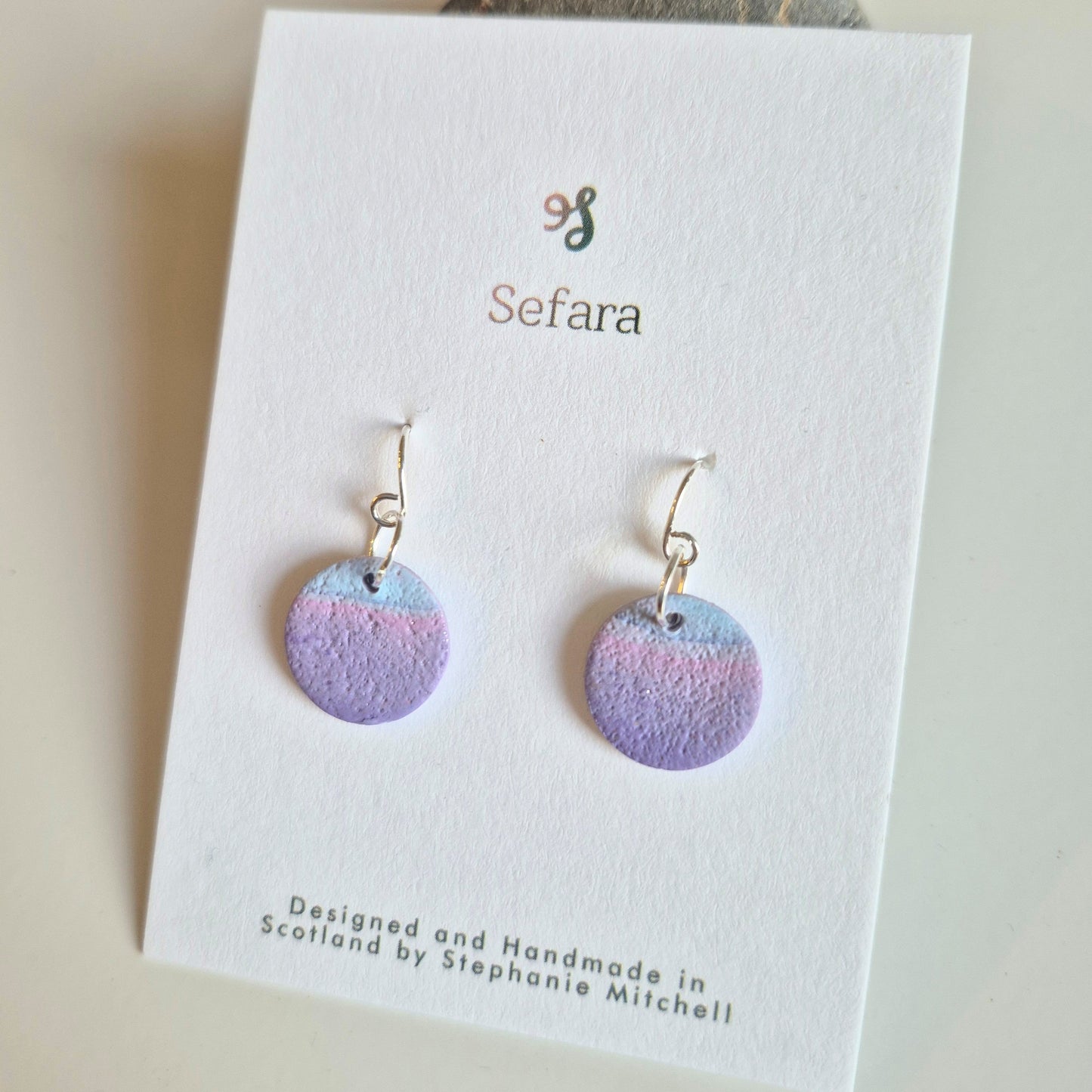 Pair of Lilac and Blue Sefara hook earrings on a branded card