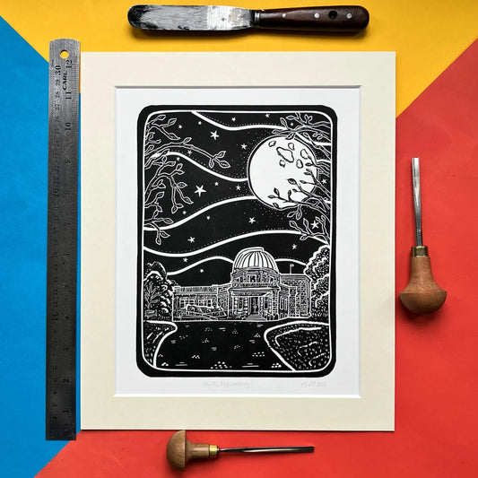 Framed black and white lino print of the Mills Observatory under a moonlit sky, surrounded by tools on a colourful background.