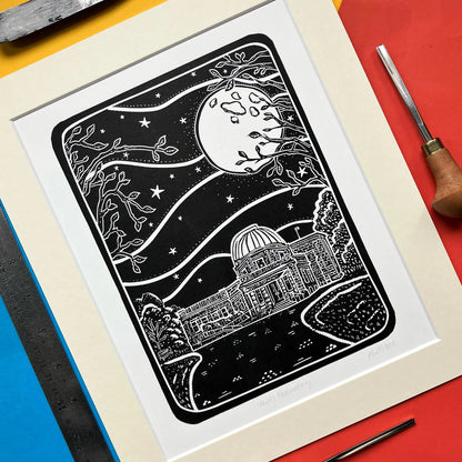 Framed black and white lino print of the Mills Observatory under a moonlit sky, on a colourful background.