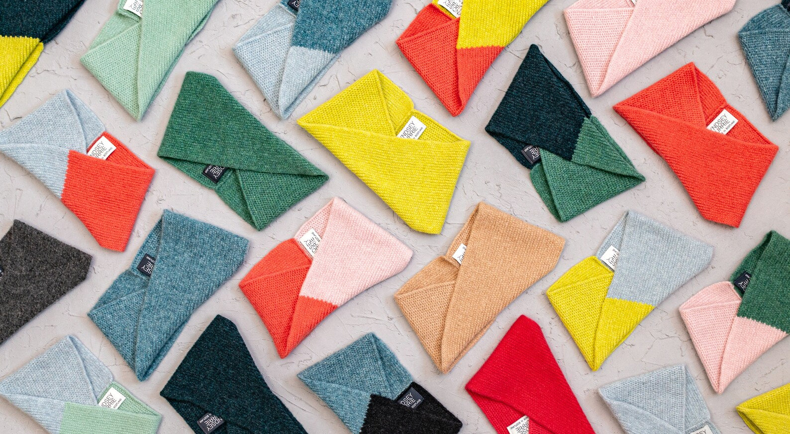 A flat-lay arrangement of multiple knitted wool headbands in assorted colours