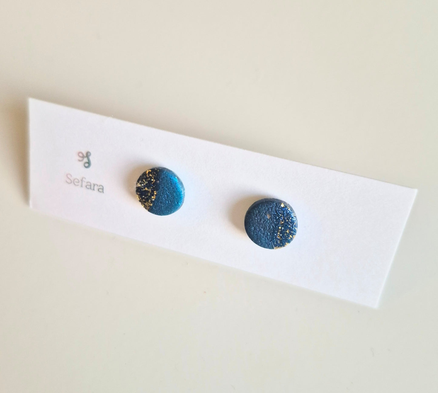Blue and gold Sefara round stud earrings on a branded card