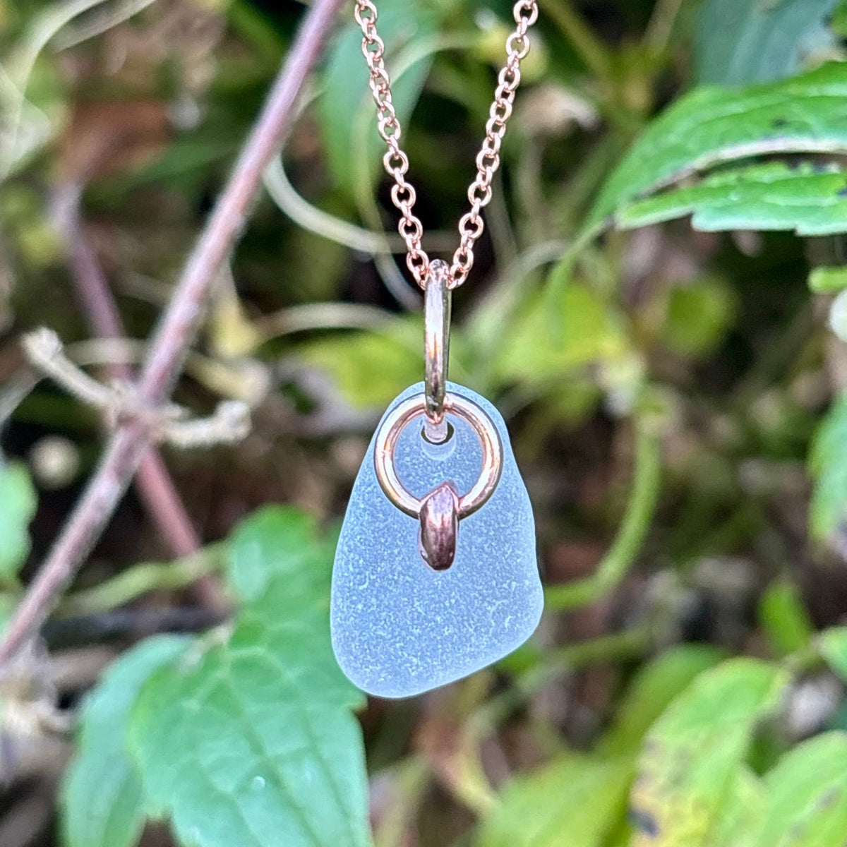 Rowan Berry Jewellery sea glass and hag stone necklace featuring frosted seafoam sea glass, a handcrafted copper hag stone and two bronze hoops on a rose gold-plated chain.