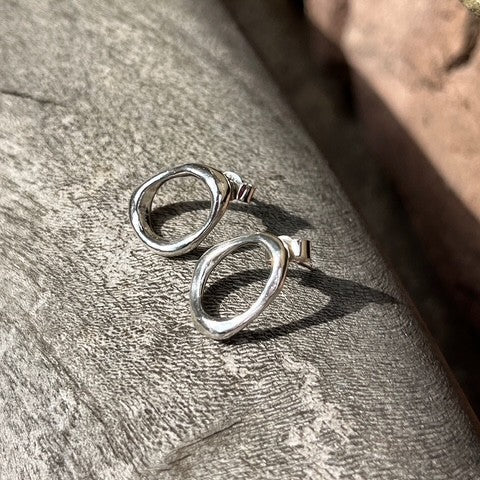 Close-up of a pair of minimalist solid sterling silver pebble stud earrings on posts