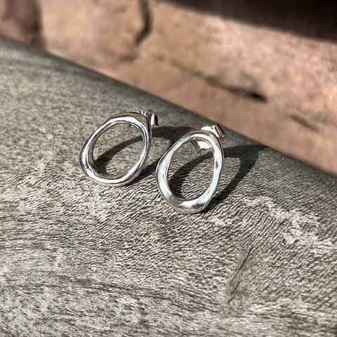 Close-up of a pair of minimalist solid sterling silver pebble stud earrings on posts