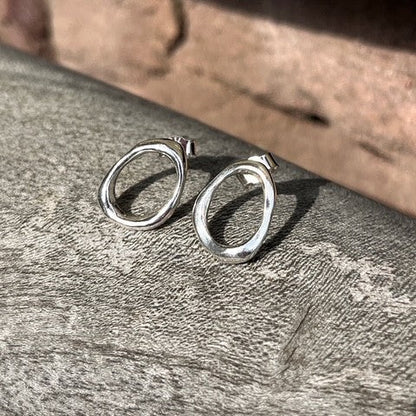 Close-up of a pair of minimalist solid sterling silver pebble stud earrings on posts