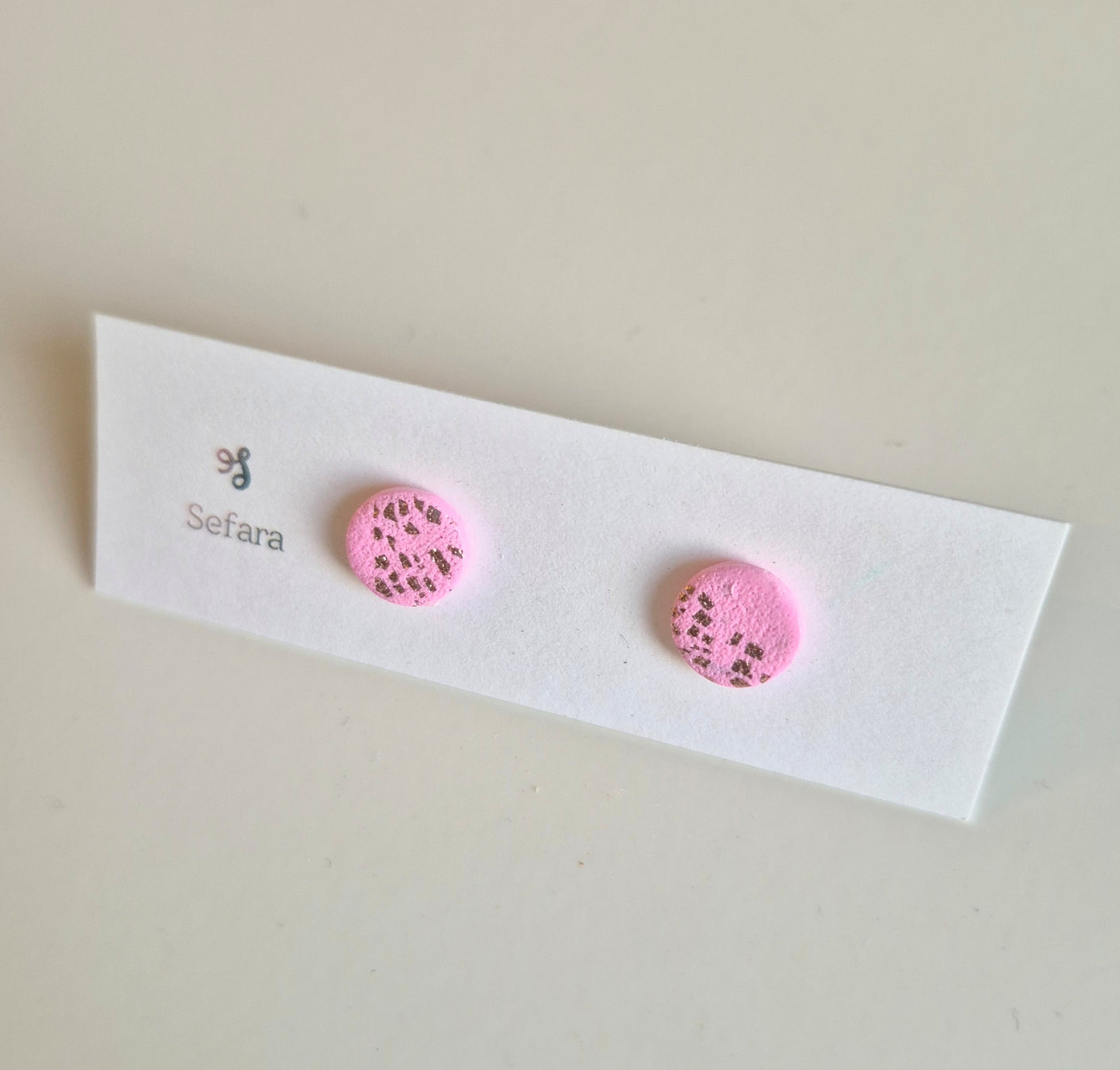 Pink and gold Sefara round stud earrings on a branded card