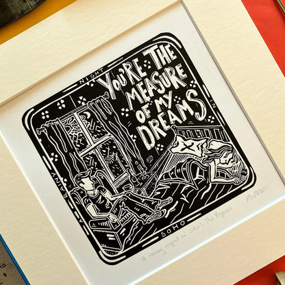 An original black and white linocut print featuring imagery inspired by The Pogues song 'A Rainy Night in Soho', mounted on antique white card.