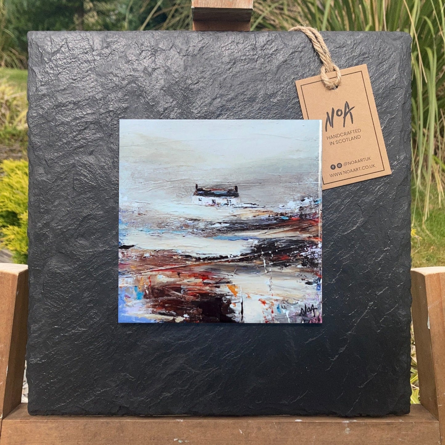 A ceramic tile print of a colourful painting titled 'Rolling Fog', showing a small house nestled in the Scottish Highlands, available mounted on natural slate or framed.