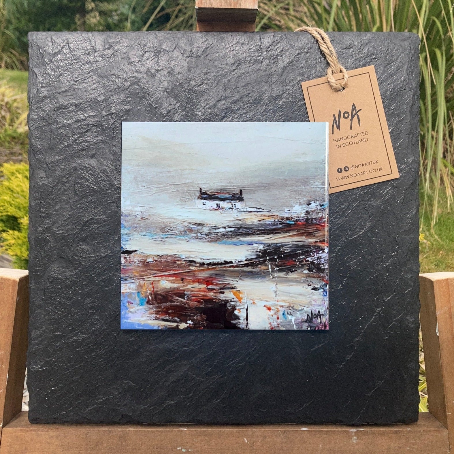 A ceramic tile print of a colourful painting titled 'Rolling Fog', showing a small house nestled in the Scottish Highlands, available mounted on natural slate or framed.