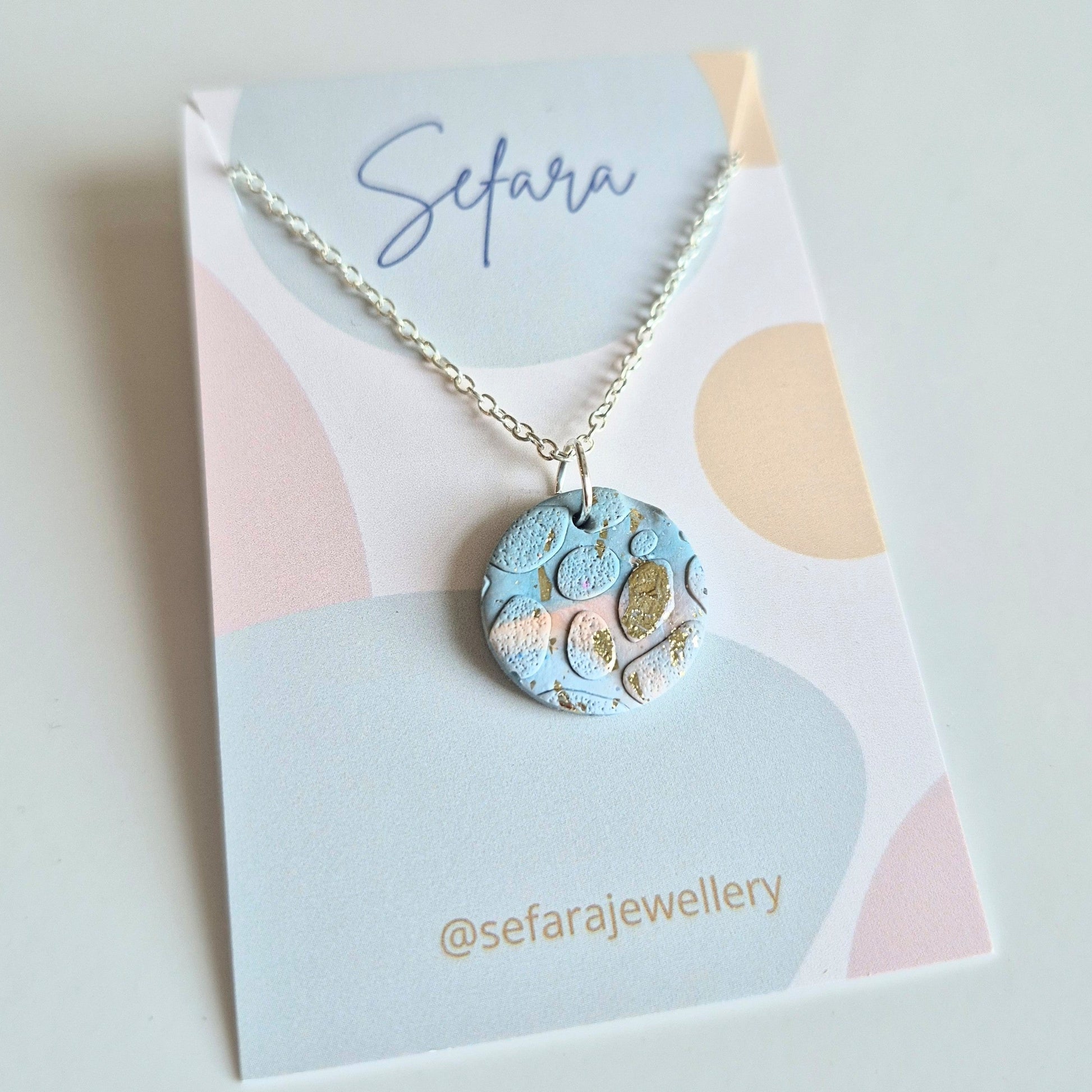 Blue Sand round pendant necklace with a unique design on a Sefara branded card