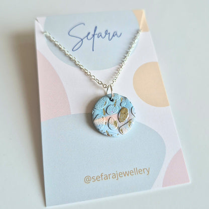 Blue Sand round pendant necklace with a unique design on a Sefara branded card