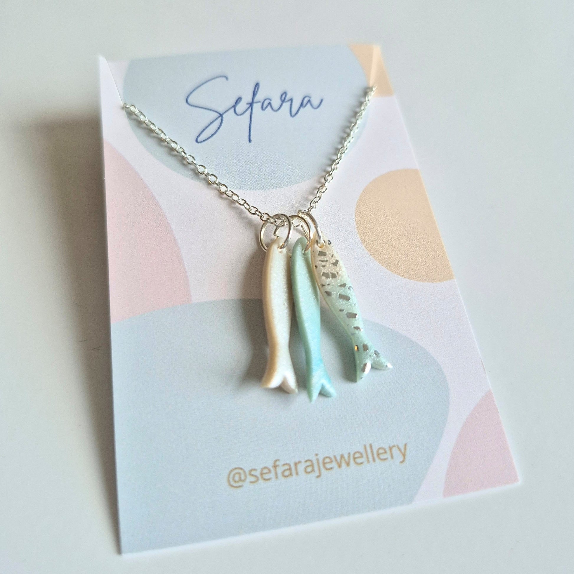 Necklace with three fish charms on a 'Sefara' branded card