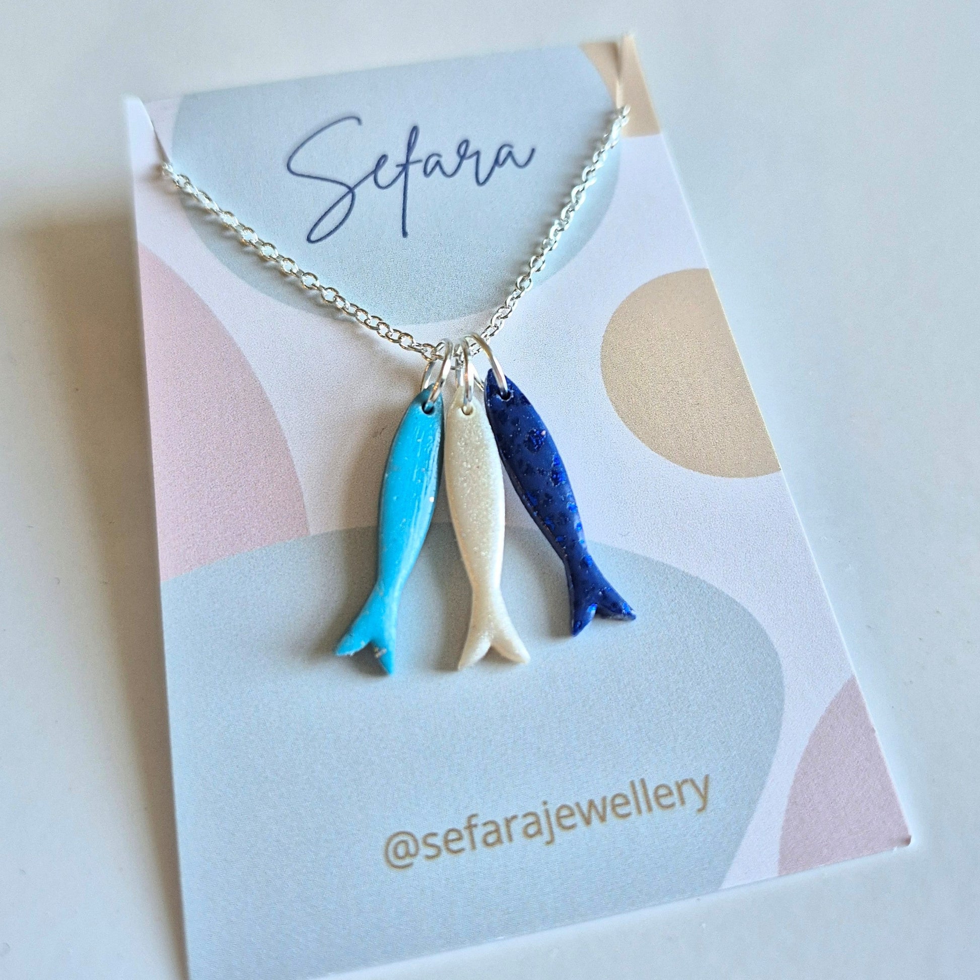 Necklace with three fish charms on a 'Sefara' branded card