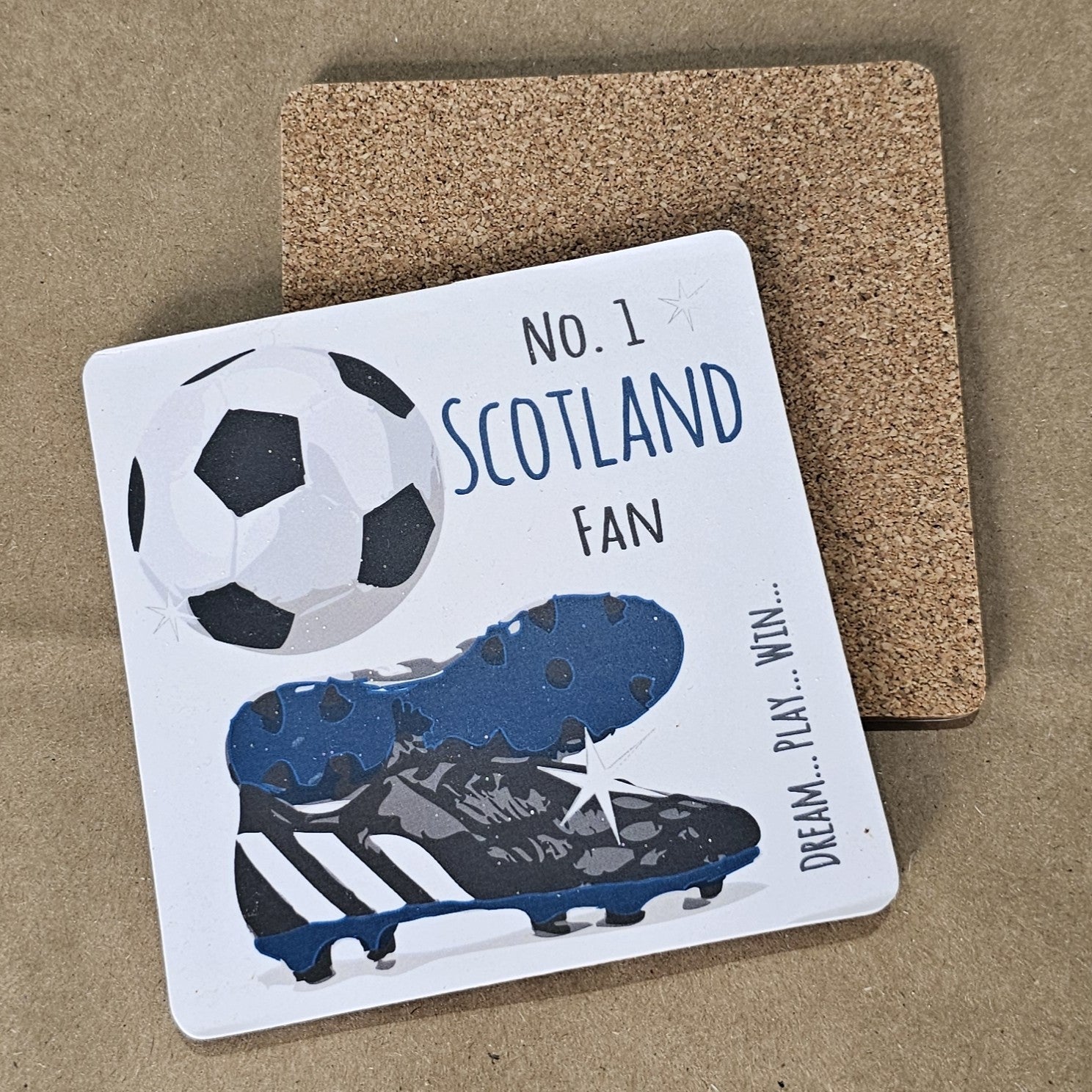 A square coaster with a cork base, featuring a football design with the text 'NO. 1 SCOTLAND FAN' and an image of a soccer ball and cleats.